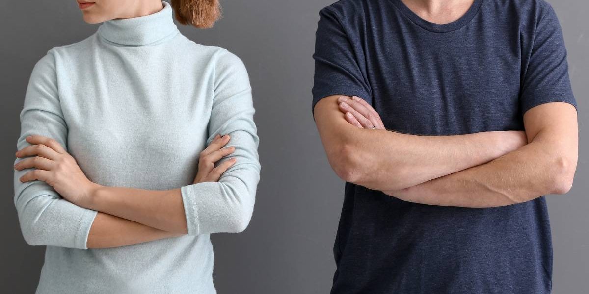 A man and a woman standing next to each other with their arms crossed. They are either seperated or divorced.