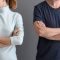 A man and a woman standing next to each other with their arms crossed. They are either seperated or divorced.