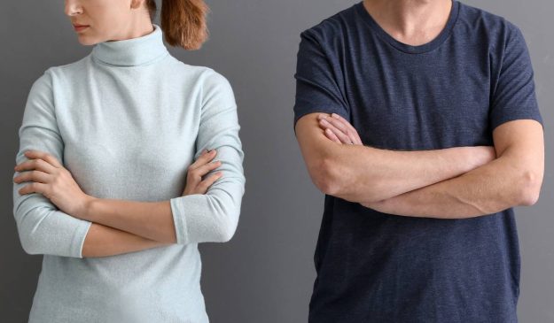 A man and a woman standing next to each other with their arms crossed. They are either seperated or divorced.